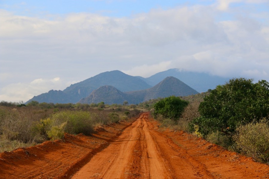 Red murram road through green countryside